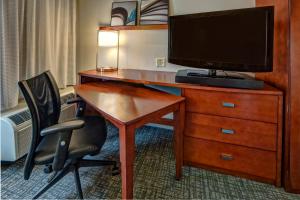 a hotel room with a desk with a tv and a chair at Courtyard by Marriott Memphis Southaven in Southaven