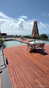 a wooden deck with a table and an umbrella at Flat Mar de Campas Beach Tamandaré in Tamandaré