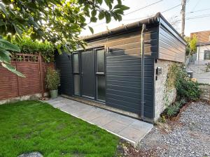 a black shed with a door on the side of a yard at Brook Lodge in Winford