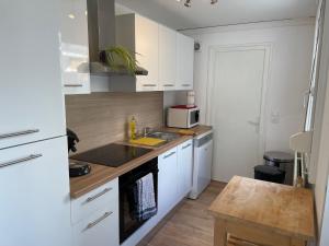 a small kitchen with white cabinets and a sink at Maisonnette 2 chambres avec cour in Haubourdin