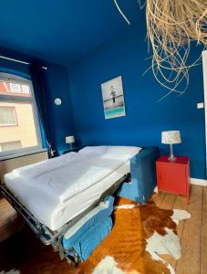 a bed in a room with a blue wall at CLS Große City Altbau Wohnung für 4 Personen mit XXL Dusche, neues Bad, Dielen, Schlafsofa 160x200 mit 20cm Matratze, Smart TV & schnellem WLAN in Hildesheim Ost, Nähe HAWK, Uni, Bosch, Ostbahnhof, A7 in Hildesheim
