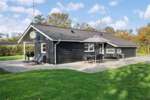 a small house with a patio and an umbrella at C11148-Hemmet-Lappedykkervaenget-22 in Hemmet