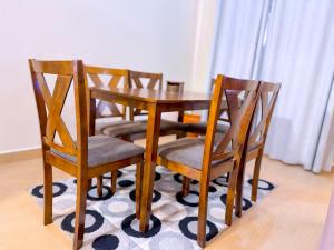 a wooden table with four chairs on a rug at 3-bedroom Spacious Munyonyo Home in Kampala +8 photos