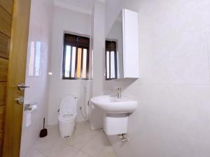 a white bathroom with a toilet and a sink at 3-bedroom Spacious Munyonyo Home in Kampala