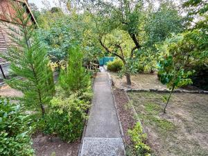 a path in a garden with trees and bushes at Vöröspart Vendégház in Kulcs