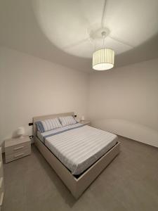 a white bedroom with a bed and a lamp at La Lupa in Bronte +4 photos