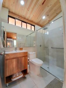 ein Badezimmer mit Toilette und Glasdusche in der Unterkunft El Rincón del Lago Escapada Privada en el Sisga in Chocontá