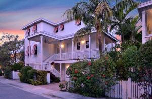 a white house with a white fence and a palm tree at Mother Ocean in Key West