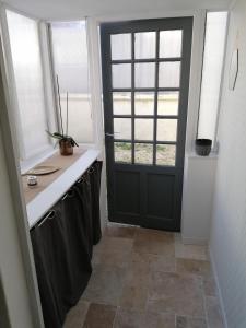 a kitchen with a black door and a window at Charmante petite maison de ville à 20 minutes de la mer in Giberville