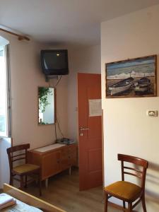 a room with two chairs and a desk and a television at Guest House Attilia in Cres