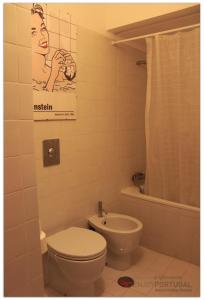 a bathroom with a toilet and a poster of a woman at Feelings Aveiro Apartment in Aveiro +17 photos