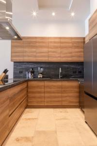 a kitchen with wooden cabinets and a stainless steel refrigerator at 2 Bedroom Residence with Terrace & Grill Live Aqua La Paz in La Paz