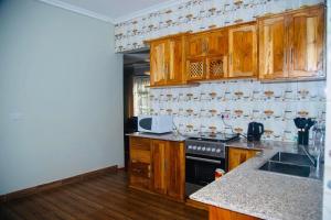 a kitchen with wooden cabinets and a counter top at Hillside Home-Fully furnished home near Ngorongoro in Karatu