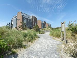 a dirt road leading to a building with tall grass at Apartment near Groote Keeten Beach in Groote Keeten