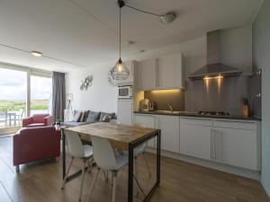 a kitchen and a living room with a table and chairs at Apartment near Groote Keeten Beach in Groote Keeten