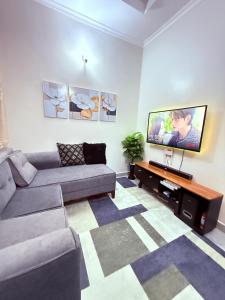 a living room with a couch and a flat screen tv at Millan House in Dar es Salaam