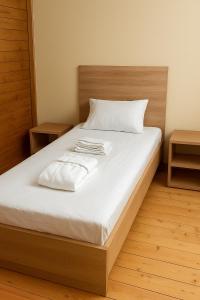 a bed with white sheets and two towels on it at flower land in Kutaisi