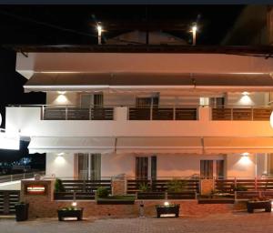 a large white building with lights on it at night at Filippos studios in Leptokaria
