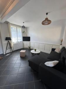 salon z czarną kanapą i telewizorem w obiekcie Charmante petite maison en plein centre-ville w mieście Mayenne