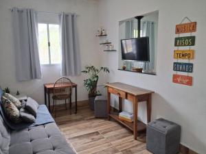a living room with a couch and a flat screen tv at Praia, piscina, churrasco e convívio com animais in Itanhaém