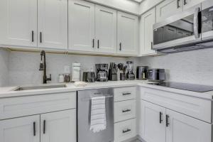 a white kitchen with white cabinets and appliances at Luxury Private Apt at Disney Area in Orlando +5 photos