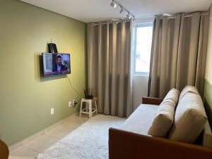 a living room with a couch and a tv on the wall at Apê com Ar condicionado in Cascavel