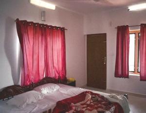 1 dormitorio con 1 cama con cortinas rojas y ventana en Rasra building, 