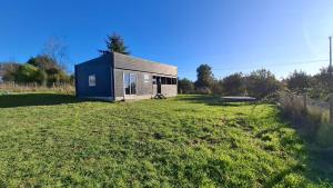 une petite maison sur un champ herbeux avec un bâtiment dans l'établissement Casa en Frutillar, à Frutillar