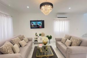 un salon avec deux canapés et une télévision dans l'établissement Elegante Casa Estrella Marina 117 Pool BBQ, à La Romana