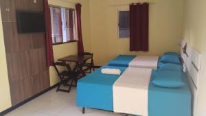a room with two beds and a table and a television at Hospedagem Beira Mar in Belém