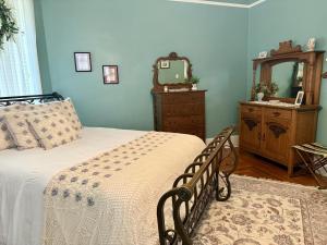 a bedroom with a bed and a dresser and a mirror at The Redbud Room at The Judges Chambers in Guthrie +2 photos