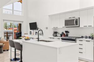 a white kitchen with a sink and a microwave at 3BR Escape BBQ, Balcony, Near Banff & DT in Canmore