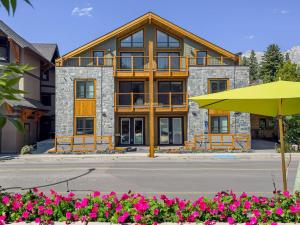 a large building with a yellow umbrella in front of it at 3BR Escape BBQ, Balcony, Near Banff & DT in Canmore