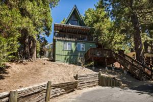 una casa verde en una colina con una valla de madera en Casa Huntsted A-Frame Cabin near Snow Valley, en Running Springs