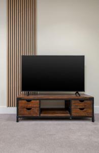 スターリングにあるStirlings Hidden and Tranquil Studio Apartmentの木製エンターテイメントセンターの上に座って薄型テレビを設置