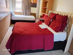 a hotel room with a bed with red pillows at M Palace Guest House in Kempton Park