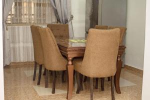 a dining room table with chairs and a wooden table at EFFAZ Apartments Airport Road Lugbe in Abuja