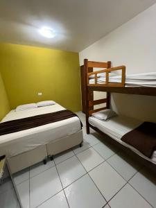 a bedroom with two bunk beds and a yellow wall at Casa Porto do Amor in Porto De Galinhas