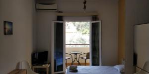 a bedroom with a bed and a balcony with a table at Thaleia Studios & Apartments in Kavos