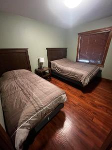 two beds in a room with wooden floors and a window at Grizzly Den in Valemount