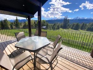 a patio with a glass table and chairs on a deck at The Westview Cabin in Valemount