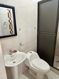 a bathroom with a toilet and a sink and a shower at Hotel Avenida 15 in Melgar +11 photos