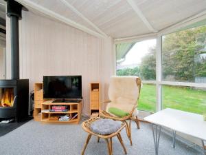 a living room with a chair and a television at 8 person holiday home in Gilleleje in Udsholt Sand +18 photos