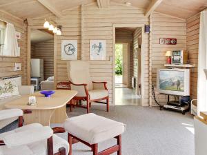 a living room with a tv and a table and chairs at Cozy Log Cabin Retreat-By Traum in Oksbøl