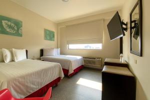 a hotel room with two beds and a flat screen tv at Hotel Urban Express in Villahermosa