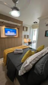a bedroom with a large bed with a tv on the wall at Studio Luxuoso in Cabo Frio