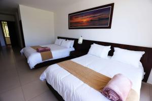 タバベラにあるZakua Gardensの白いシーツが敷かれたホテルの部屋にベッドが2つある