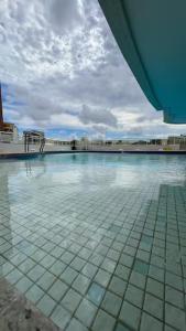 a swimming pool with a tile floor and a building at Studio Luxuoso in Cabo Frio