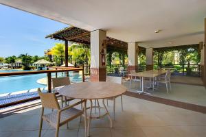 un patio avec tables et chaises à côté d'une piscine dans l'établissement Wai Wai Resort #307 - Apê luxuoso por Carpediem, à Cumbuco 63 autres photos