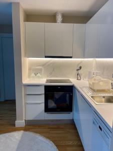a white kitchen with a sink and a stove at Skopje City Center 1BR Apt - Free Parking & Wi-Fi in Skopje +5 photos